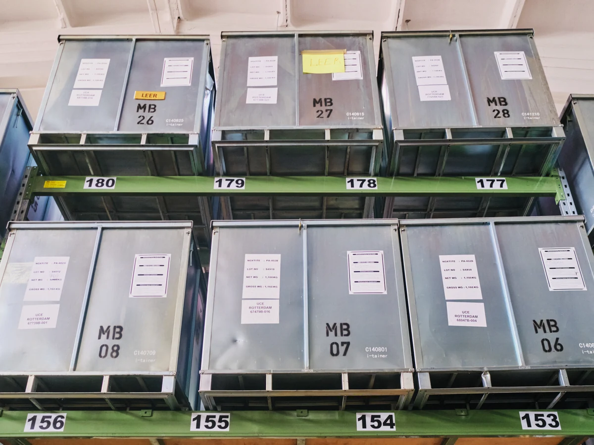 Gestapelte, beschriftete Metallboxen in einer Lagerhalle der Anlage